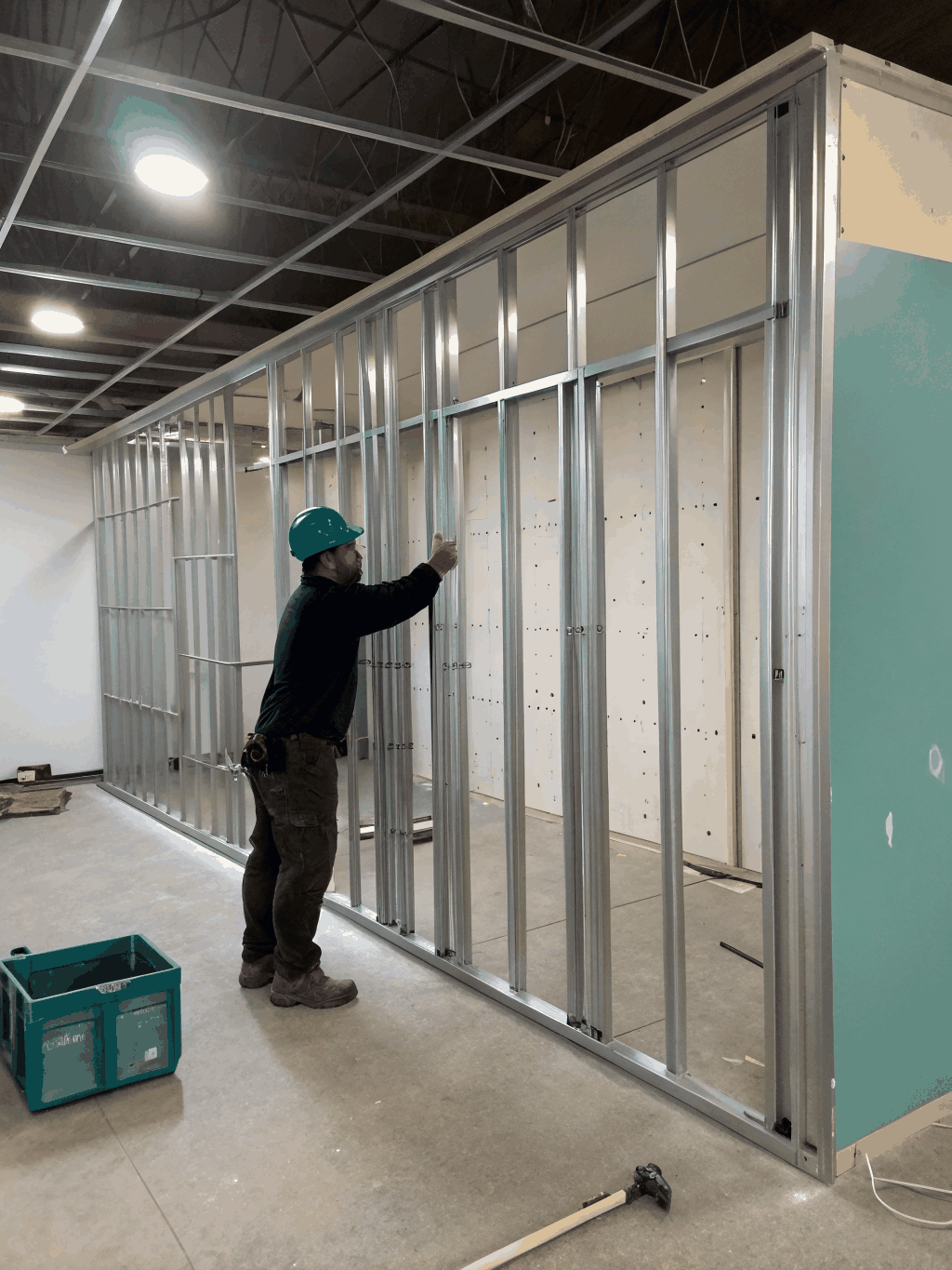 Professional framing crew installing metal studs in a commercial interior space